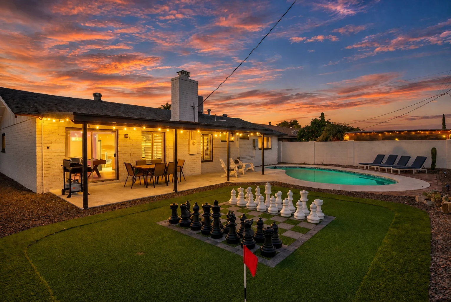 Private backyard with giant chess and pool at twilight